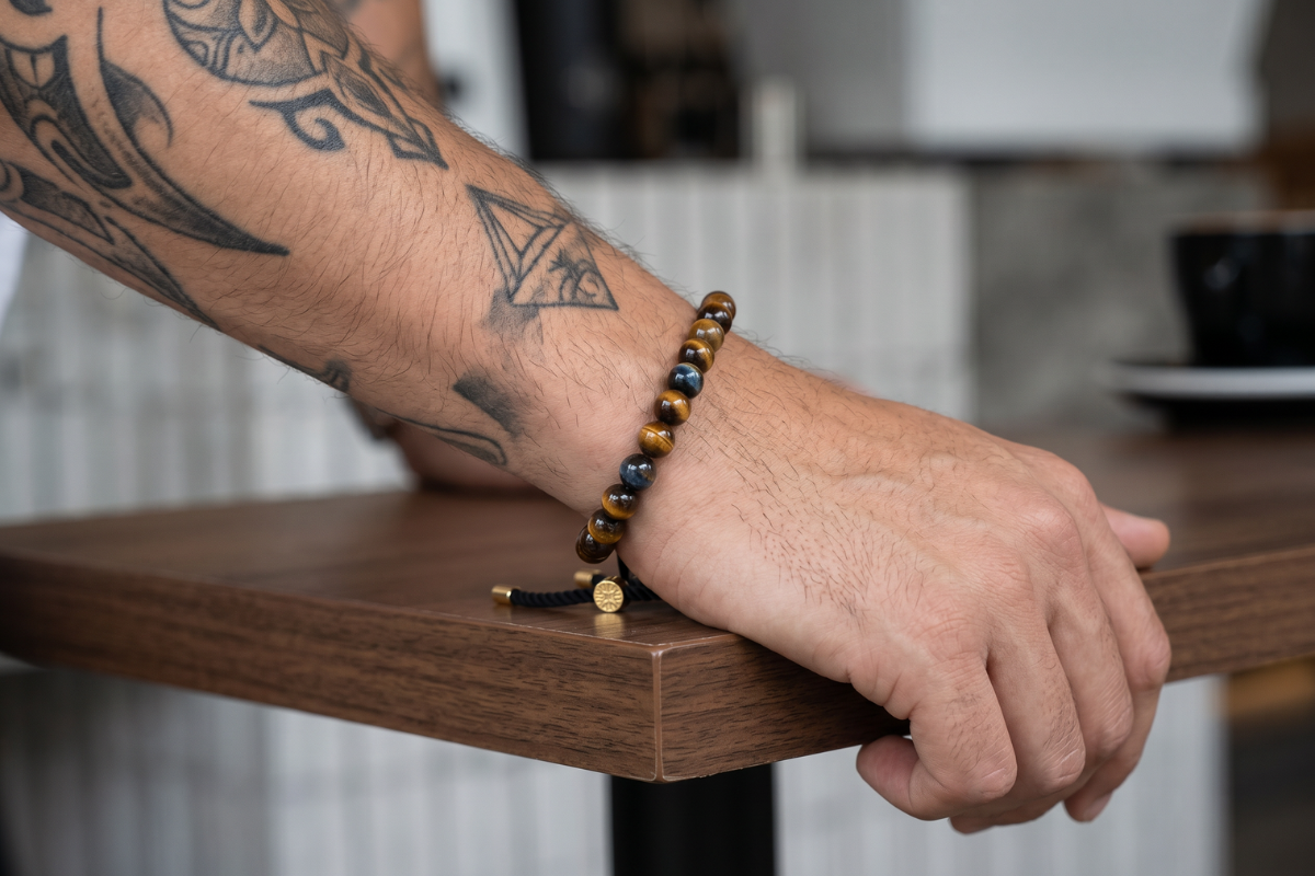 �delstensarmb�nd med gyldenbrune tiger�je perler, sort snor og 18K guldbelagt glidel�s