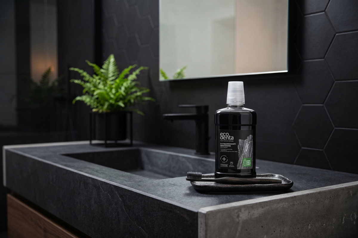 En stor flaske Ecodenta Extraordinary Whitening Mundskyl. Flasken er gennemsigtig med en sort etiket med tr�kul-grafik og en smart indbygget v�skedispenser i toppen.