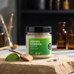 Cosmoveda Ashwagandha urtepulver i glas pr�senteret p� naturtr�, omgivet af fintmalet pulver, friske blade og rosenvand i en �stetisk apothecary-stil.