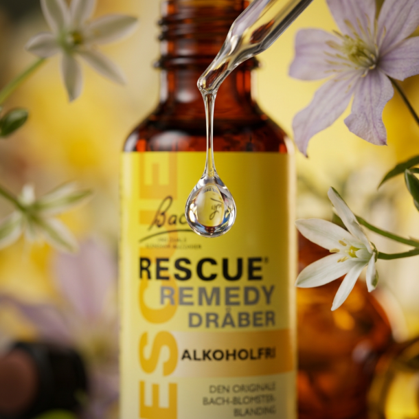 Et krystalklart makrobillede af en frisk, rund vanddr�be, der falder i fokus. Den bl�dt sl�rede baggrund kombinerer varme, optimistiske gule nuancer med sarte botaniske glimt (Fuglem�lk/Skovranke) og en subtil silhuet af en stor, 1:1 realistisk lukket m�rk ravfarvet glasflaske. Lyset er ekstremt klart, beroligende, og udstr�ler absolut indre ro, f�lelsesm�ssig balance for familien og botanisk renhed.
