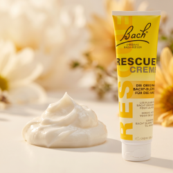 Et krystalklart makrobillede af en gener�s, struktureret klat af rig, bl�dg�rende hvid creme med sheasm�r, placeret sirligt p� en ren overflade ved siden af den store, gule 150 ml Bach Rescue Creme tube (helt uden pipetter, dr�bet�llere eller v�ske). Den bl�dt sl�rede baggrund kombinerer lyse, bl�de cremehvide nuancer og varme, str�lende gyldne sol-toner, som diskret og elegant repr�senterer den botaniske renhed fra Dr. Bachs blomsteressenser. Lyset er ekstremt varmt, organisk og indbydende, hvilket fremh�ver total kosmetisk renhed og fugt uden at virke for sterilt. Knivskarpt fokus.