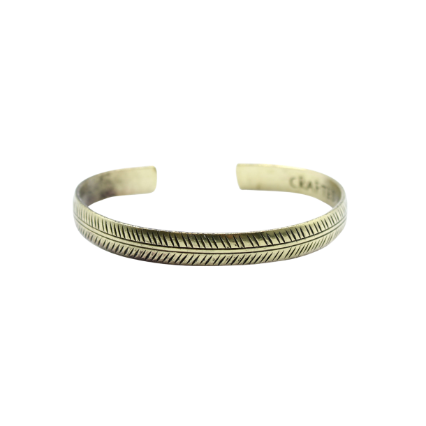 Et smalt, gyldent messingarmb�nd formet som en cuff, prydet med et fint, h�ndgraveret geometrisk Tribal Leaf bladmotiv.