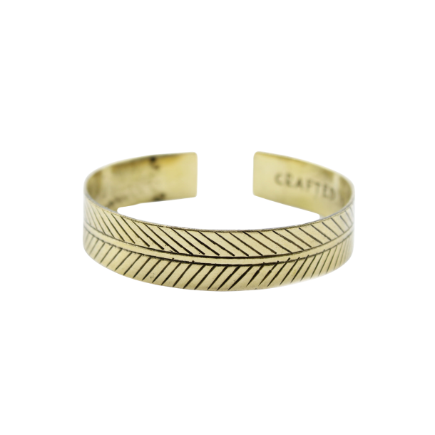 Et bredt, gyldent messingarmb�nd formet som en cuff, prydet med et dybt indgraveret geometrisk Tribal Leaf bladmotiv.
