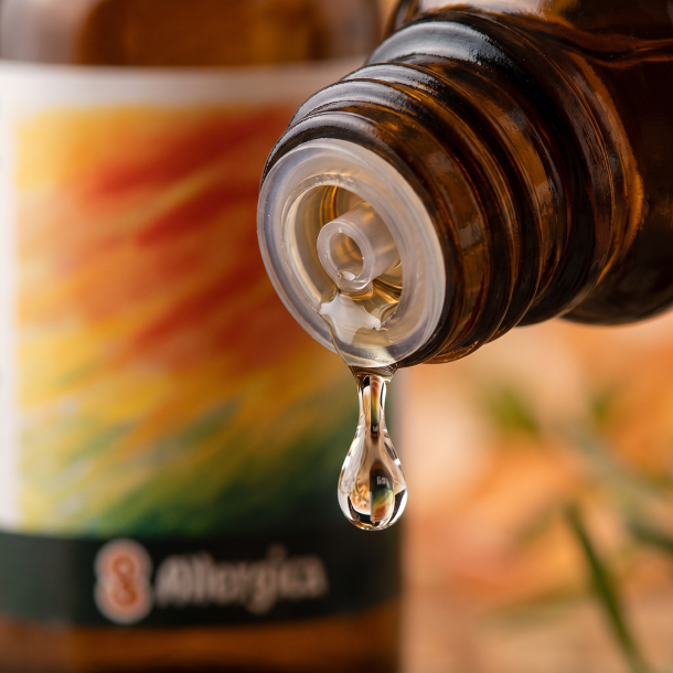 Et krystalklart makrobillede af eine vanddr�be, der falder fra den indbyggede dr�bet�ller p� eine m�rk ravfarvet glasflaske. Den bl�dt sl�rede baggrund kombinerer varme, trygge ravgyldne og bl�de orange nuancer med sm�, subtile botaniske strejf af gr�n anis og solhat (Echinacea). Lyset er blidt, omsorgsfuldt og beroligende.