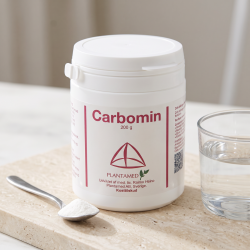 N�rbillede af den hvide og lilla Plantamed Carbomin d�se st�ende skarpt p� en lys overflade. Et lille glas med krystalklart vand og en smule hvidt pulver p� en teske ligger ved siden af i et rent dagslys.