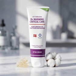 Dr. Warming fedtcreme pr�senteret p� lyst marmor, omgivet af en hvid bomuldsblomst og naturlig bivoks i et minimalistisk og rent klinisk milj�.