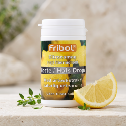 N�rbillede af den hvide og gule Fribol Citron d�se, st�ende skarpt p� en lys stenplade. En halv frisk, dugv�d citron og et par gr�nne timianblade ligger smukt spredt foran d�sen i bl�dt, lyst dagslys.