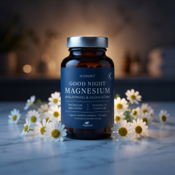 Nordbo Good Night Magnesium pr�senteret p� en m�rkebl� marmoroverflade i afd�mpet aftenbelysning, ledsaget af friske kamilleblomster, der symboliserer ro og afslapning.