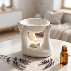 Den hvide keramiske 'Helping Hand' duftlampe pr�senteret p� et bl�dt stengulv, smukt oplyst af et fyrfadslys og omgivet af t�rrede lavendelkviste i et roligt meditationsrum.