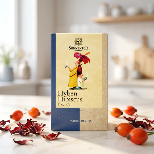 Sonnentor Hyben Hibiscus te-�ske pr�senteret p� lyst marmor, ledsaget af t�rrede r�de hibiscusblade og friske hyben i et lyst, eksklusivt k�kkenmilj�.