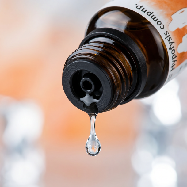 Et krystalklart makrobillede af en vanddr�be, der falder fra den indbyggede dr�bet�ller p� en 1:1 realistisk m�rk ravfarvet glasflaske. Den bl�dt sl�rede baggrund kombinerer varme, omsorgsfulde fersken- og orangenuancer (Ovaria) med afk�lende, krystallinske lyse og s�lvfarvede glimt (Stannum & Apis). Lyset er ekstremt klart, balancerende, og udstr�ler absolut kvindelig harmoni, k�lende ro i livets overgange og hom�opatisk pr�cision.