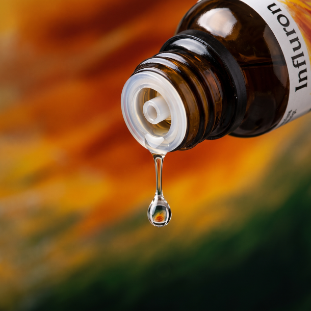 Et krystalklart makrobillede af en vanddr�be, der falder fra den indbyggede dr�bet�ller p� en m�rk ravfarvet glasflaske. Den bl�dt sl�rede baggrund br�nder i varme, gyldne rav- og br�ndte orange nuancer blandet med subtile, dybe skovgr�nne toner, der symboliserer Stormhat (Aconitum) og indre varme. Lyset er klart, opkvikkende og skarpt.