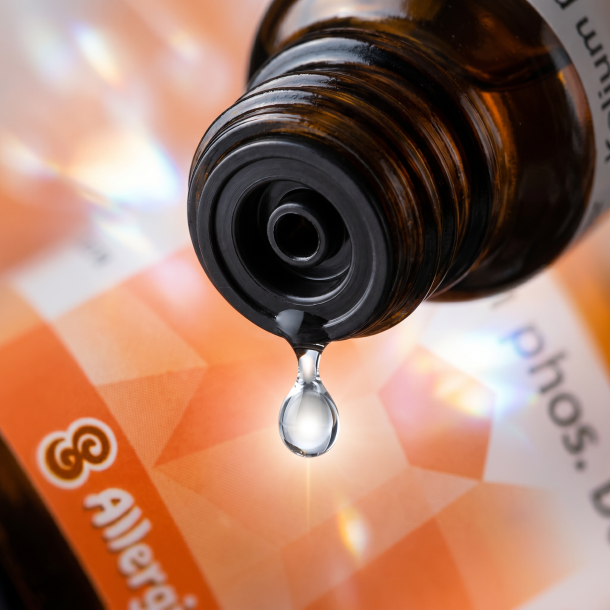 Et krystalklart makrobillede af en vanddr�be, der falder fra den indbyggede dr�bet�ller p� en 1:1 realistisk m�rk ravfarvet glasflaske. Den bl�dt sl�rede baggrund kombinerer dybe, varme orange og ferskenfarvede nuancer med lyse, krystallinske glimt af ren, lysende energi (Fosfor). Lyset er ekstremt klart, beroligende, og udstr�ler absolut nervesystems-balance, mental ro og hom�opatisk pr�cision.