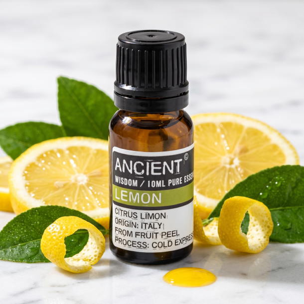 Et n�rbillede af en m�rk glasflaske med �terisk olie. Omkring flasken ligger der friske, skivede italienske citroner, gr�nne citrusblade og en skinnende dr�be gylden olie p� lyst hvidt marmor.
