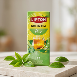 N�rbillede af den h�jformatede, lysegr�nne Lipton te�ske st�ende skarpt p� en lys stenoverflade. Friske, dugv�de, gr�nne teblade er smukt spredt foran �sken i et rent og klart dagslys.