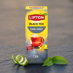 N�rbillede af den h�jformatede, gr� og gule Lipton te�ske st�ende skarpt p� en elegant overflade af m�rkegr�t skifer. En enkelt snoet bergamotte-skr�l og to gr�nne teblade ligger foran i bl�dt lys.
