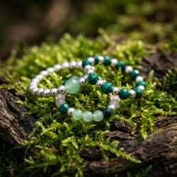 Et stemningsfuldt, bredt livsstilsbillede af et par h�nder, der b�rer 'Forest Spirit' perleringene samlet p� �n finger, mens der holdes en varm kop te i en dyb, solbeskinnet skovbund.