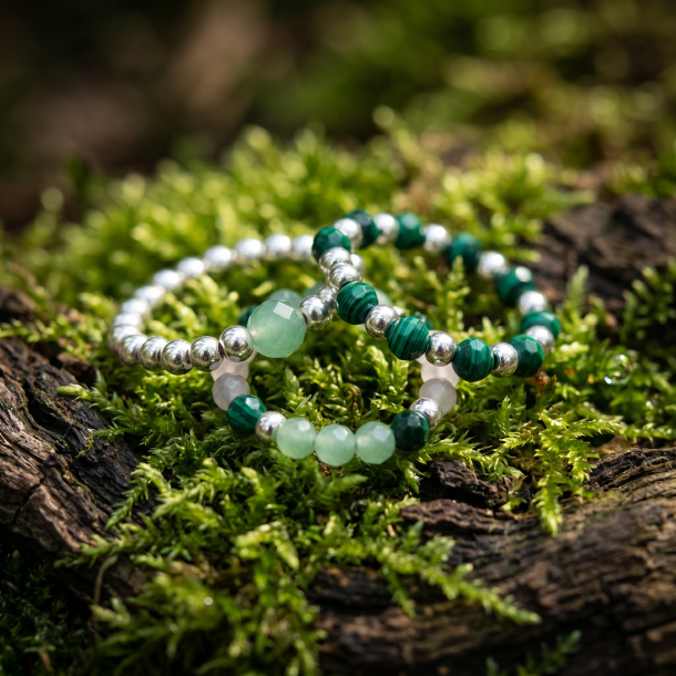 Et stemningsfuldt, bredt livsstilsbillede af et par h�nder, der b�rer 'Forest Spirit' perleringene samlet p� �n finger, mens der holdes en varm kop te i en dyb, solbeskinnet skovbund.