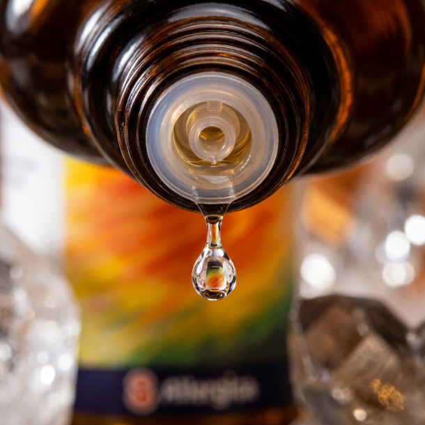 Et krystalklart makrobillede af en vanddr�be, der falder fra den indbyggede dr�bet�ller p� en m�rk ravfarvet glasflaske. Den bl�dt sl�rede baggrund kombinerer varme, dybe orange nuancer med skarpe, krystalklare glimt, der leder tankerne hen p� ren kisel (Quartz). Lyset er ekstremt klart, strukturerende, opfriskende og udstr�ler absolut indre klarhed, kropslig lethed og mineralsk styrke.
