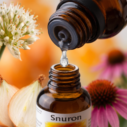 Et krystalklart makrobillede af en vanddr�be, der falder fra den indbyggede dr�bet�ller p� en m�rk ravfarvet glasflaske. Den bl�dt sl�rede baggrund kombinerer varme, solrige orange nuancer med milde, botaniske strejf af hvidguld fra Kepal�g (Allium) og m�rk rosa fra Solhat (Echinacea). Lyset er ekstremt klart, opfriskende og udstr�ler absolut harmoni, kropslig lethed og botanisk styrke.