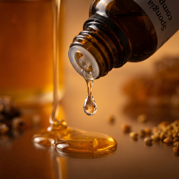 Et utroligt smukt n�rbillede af en enkelt klar dr�be, der falder direkte fra dr�bet�lleren p� en m�rkegul rav-flaske. I baggrunden anes en tyk dr�be gylden honning. Lyset er bl�dt og varmt, hvilket giver et udtryk af ro, velv�re og naturens renhed.