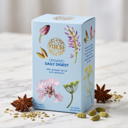 N�rbillede af den lysebl� Tulsi te�ske st�ende skarpt p� et lyst marmorbord, elegant omkranset af sm�, delikate stjerneanis, fennikelfr� og hele kardemommekapsler i et krystalklart dagslys.