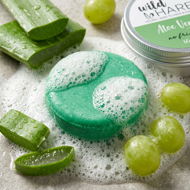 Et n�rbillede af en rigt skummende, botanisk gr�n shampoo bar omgivet af friske, saftige aloe vera blade og gr�nne vindruer.