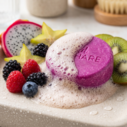 Et n�rbillede af en rigt skummende, levende lilla shampoo bar omgivet af friske sommerb�r og eksotiske frugter.