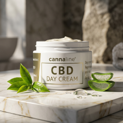 Cannaline dagcreme pr�senteret p� hvidt marmor med guld�rer, omgivet af friske gr�nne teblade, aloe vera og fugtgivende dr�ber.